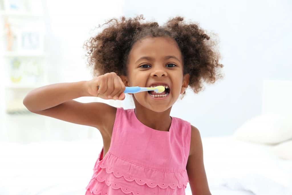 child brushing teeth with fluoride toothpaste