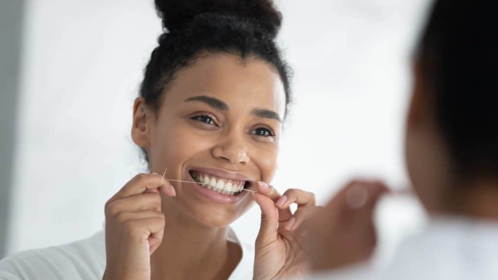 women flossing to maintain good oral habit